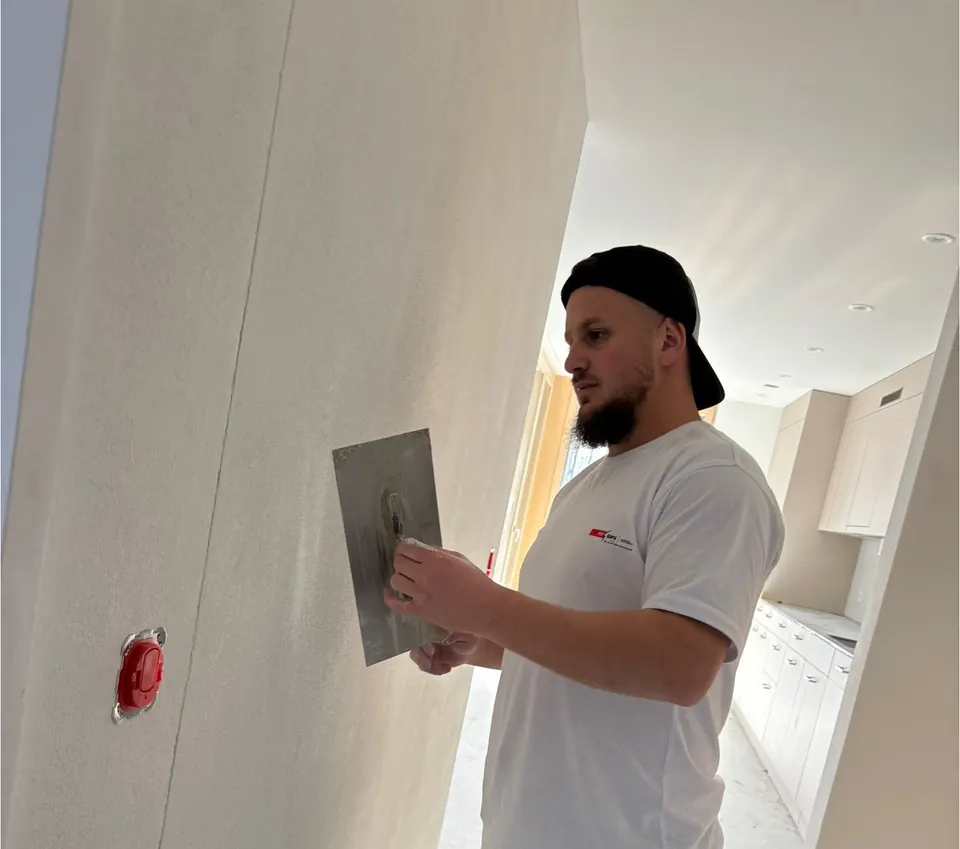 Fitim, Geschäftsführer der Fit Gips GmbH, glättet eine Wand